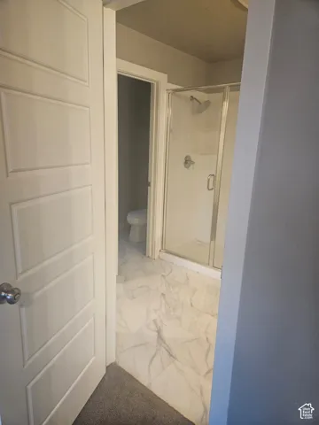 Bathroom featuring a glass-enclosed shower, white tile flooring, and a panel-style door