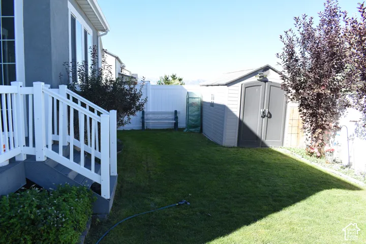 Expansive green lawn, white privacy fencing, and a built-in storage shed