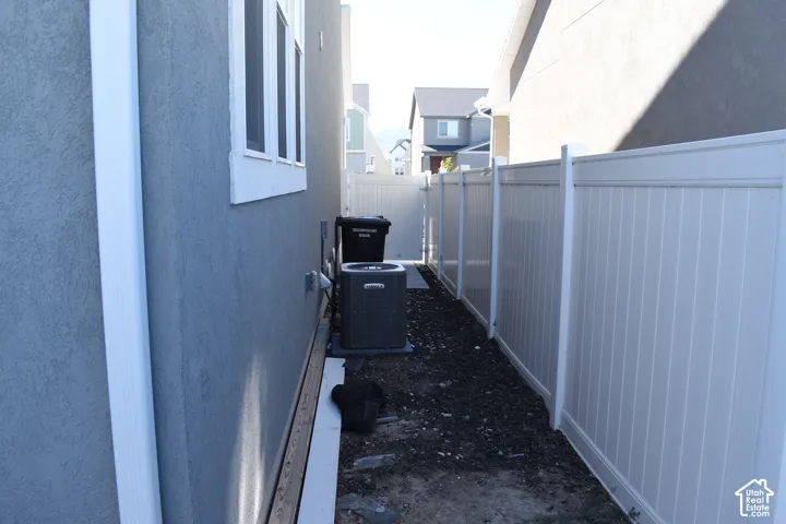 Stucco exterior with white-framed windows, white gutter system, and white privacy fencing