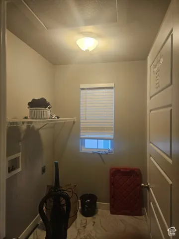 Recessed wall box with hookups, single window with blinds, overhead lighting fixture, and wire shelving