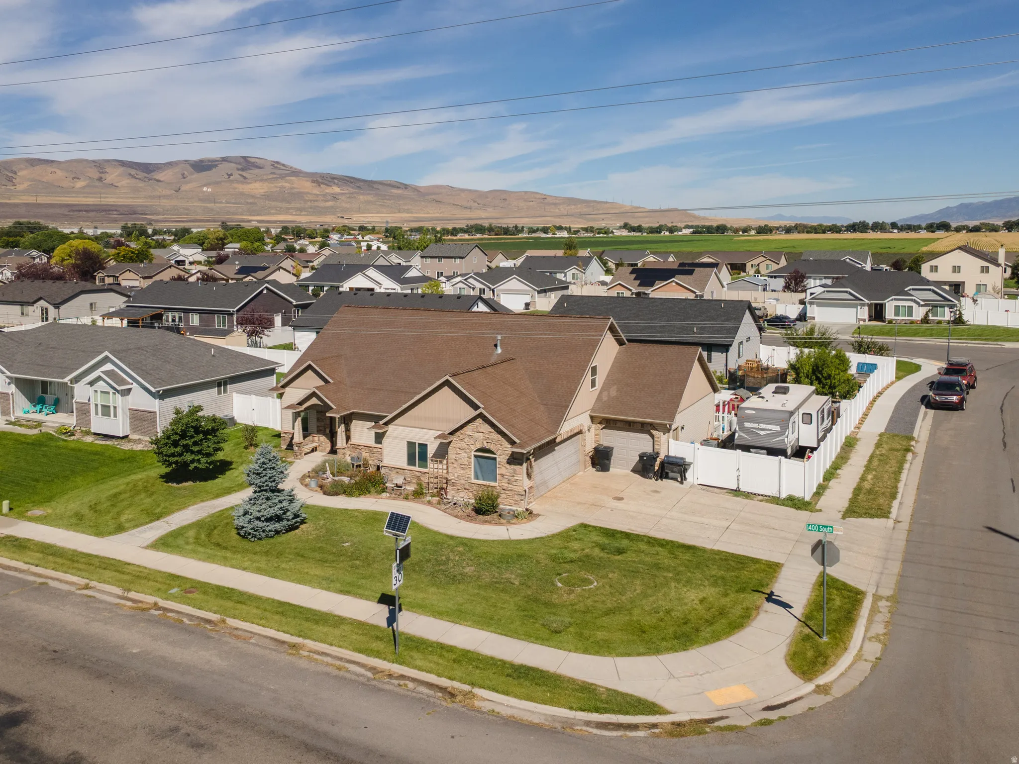 Corner lot residence featuring a stone and stucco exterior, an attached two-car garage, mature landscaping, and mountain scenery