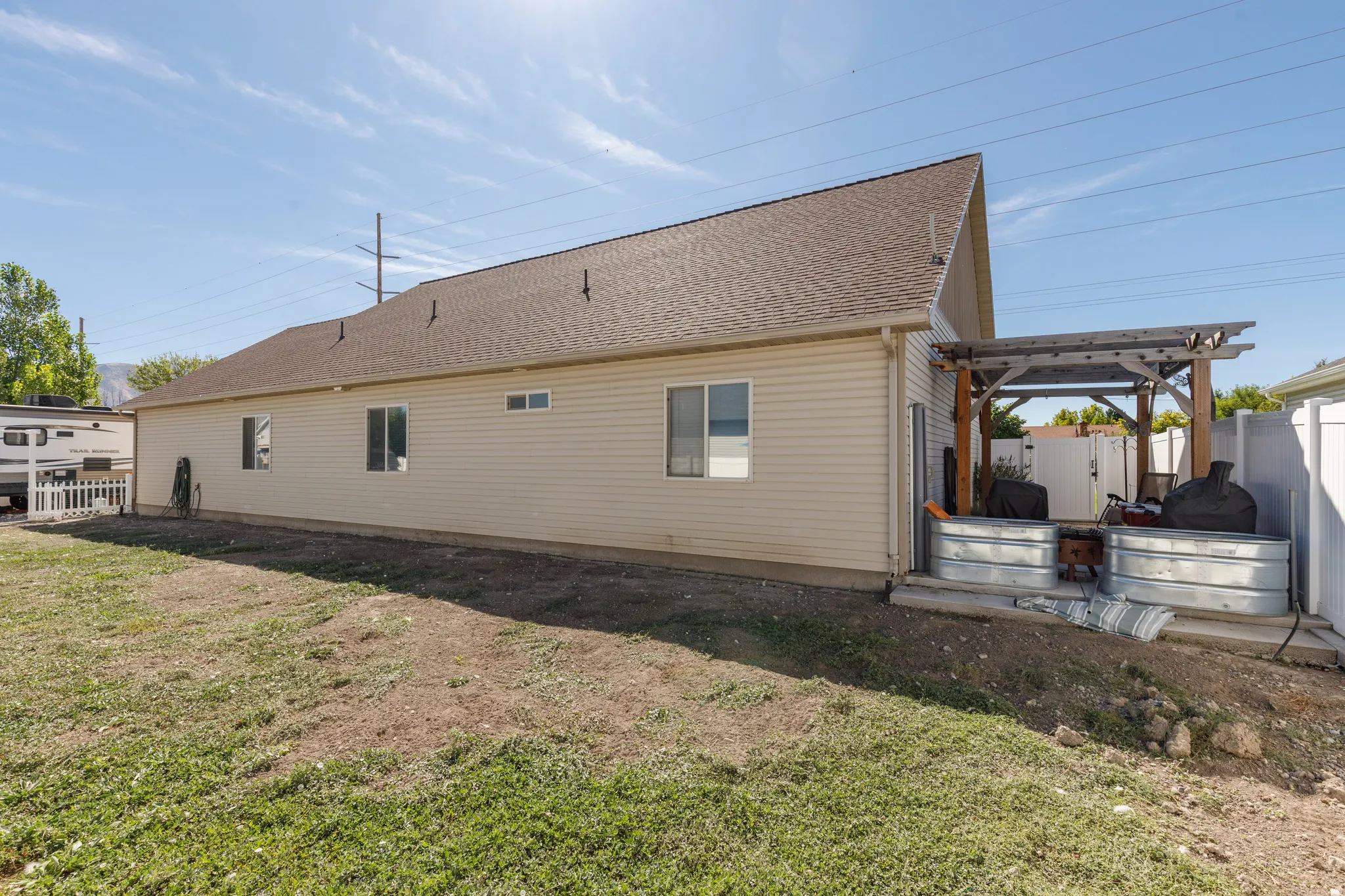 Rear exterior featuring a brown shingle roof, neutral-toned siding, multiple windows, and a wood pergola
