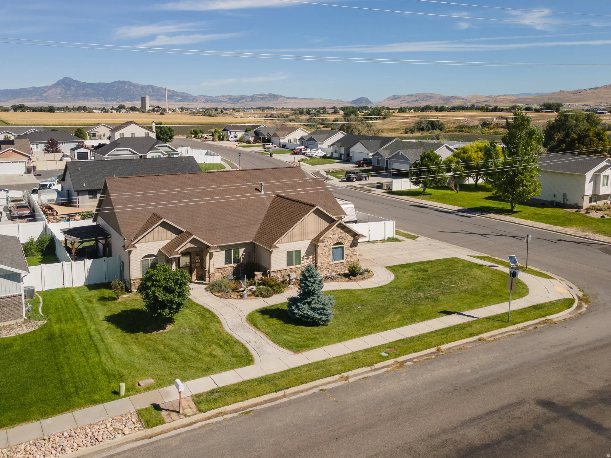 Ranch-style exterior with stone and siding accents, a prominent front yard with mature landscaping, and a concrete driveway