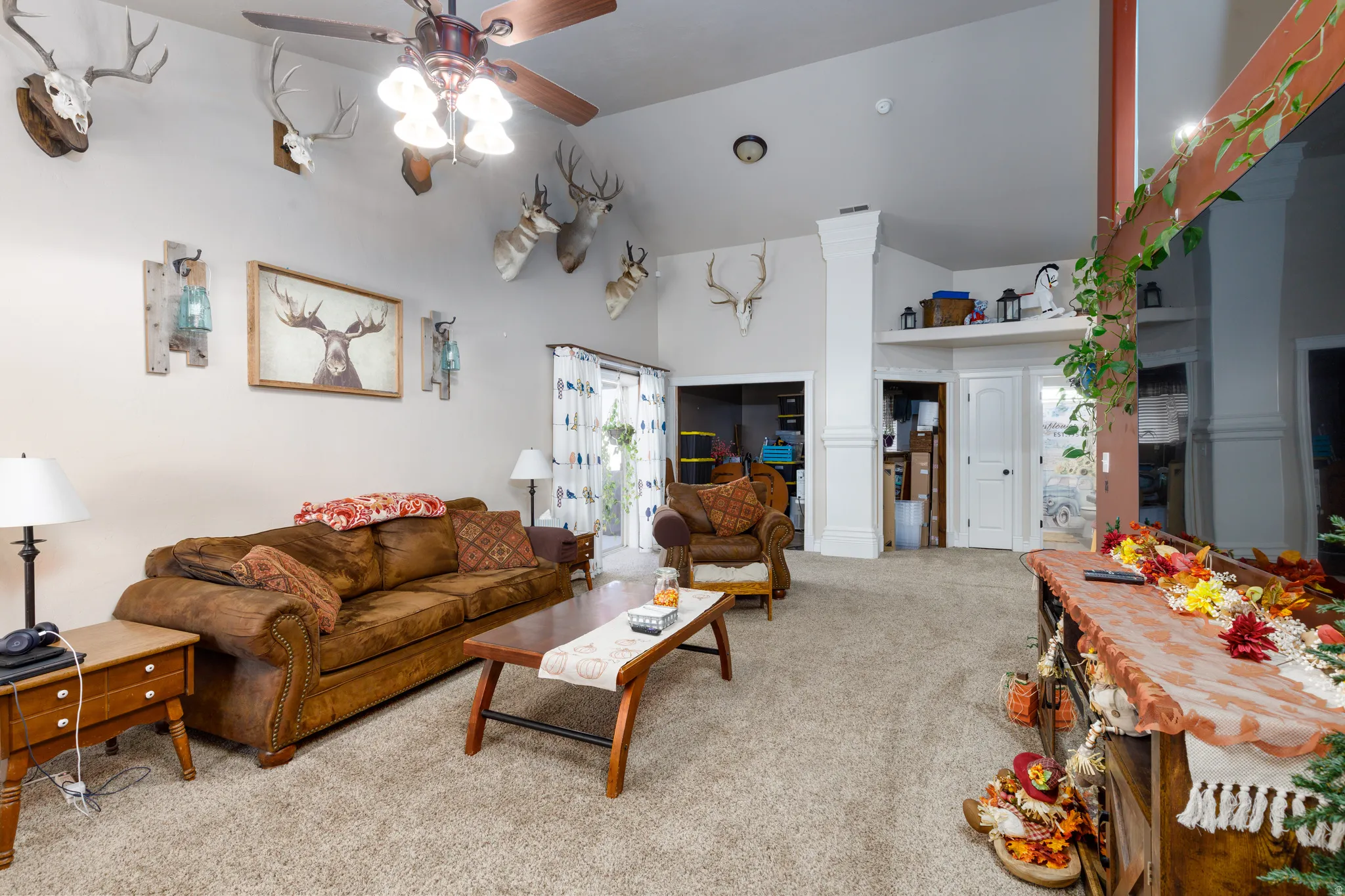 Vaulted ceiling with a ceiling fan, light-toned carpet, and a white interior door