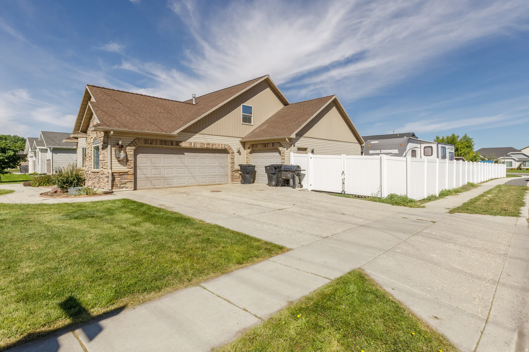 Exterior featuring stone accents, a multi-car garage, and a vinyl privacy fence