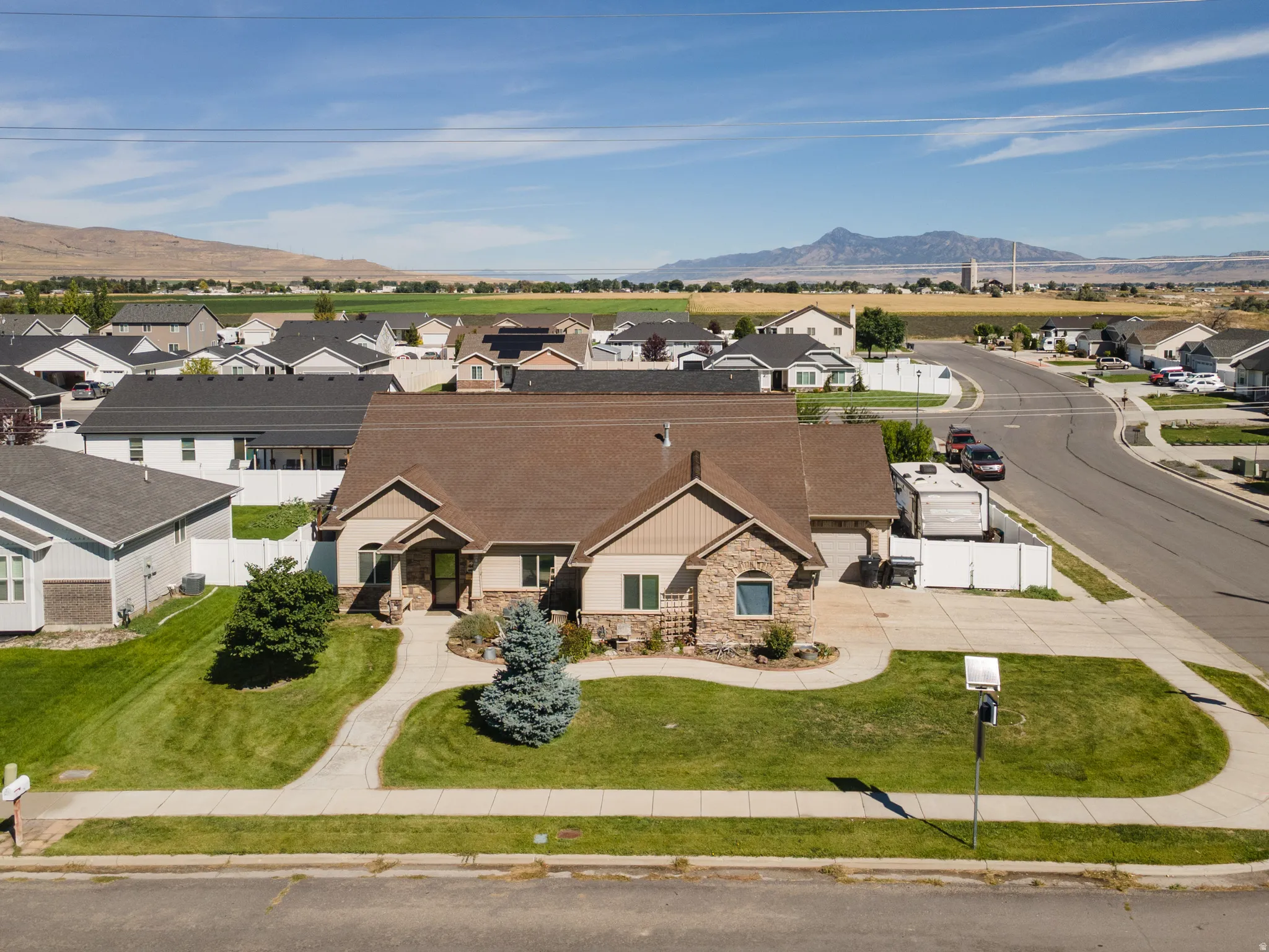 Stone and stucco exterior, prominent front gable, attached garage, concrete driveway, and a paved walkway leading to the entrance