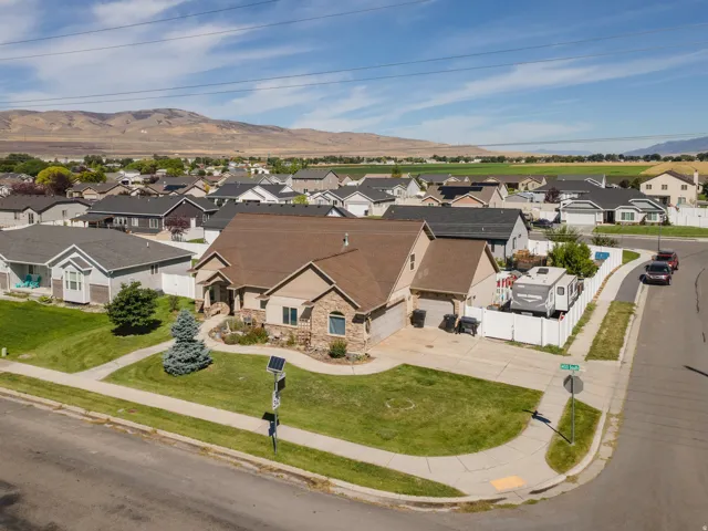 Corner lot residence featuring a stone and stucco exterior, an attached two-car garage, mature landscaping, and mountain scenery