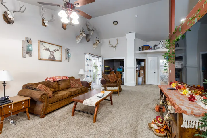 Vaulted ceiling with a ceiling fan, light-toned carpet, and a white interior door