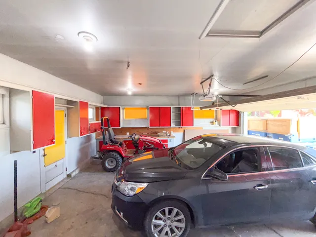 Garage space featuring overhead lighting, built-in cabinetry, a workbench, and a concrete floor