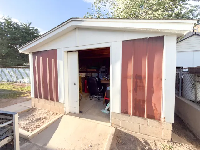 Detached structure with white siding and corrugated metal accents, set on a block foundation