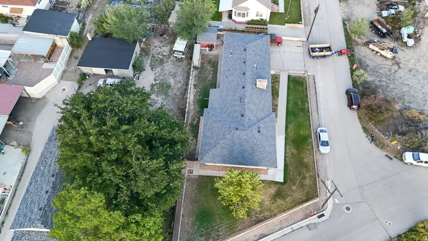 Property with a gabled roof, mature trees, a detached auxiliary building, and a paved street frontage