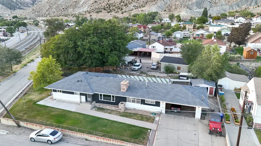 Single-story residence with a dark gray shingle roof, integrated carport, and stone chimney