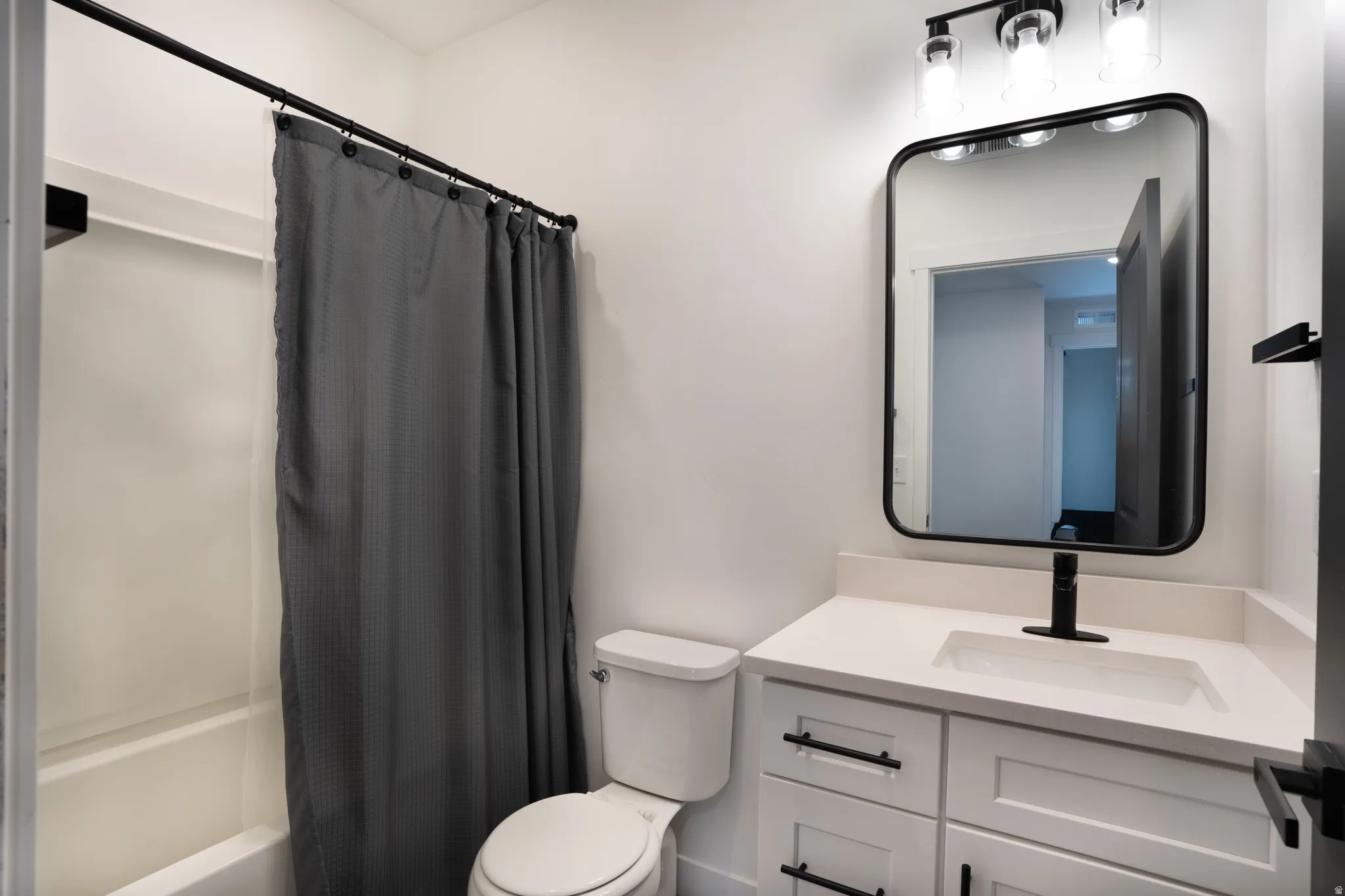 White vanity with matte black hardware, integrated sink, and quartz countertops
