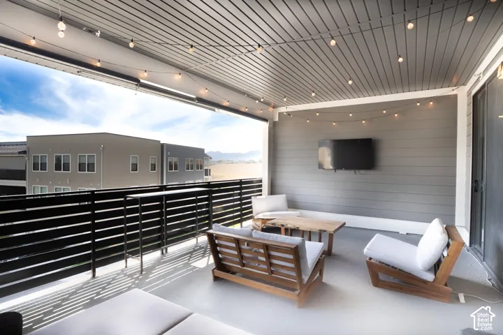 Covered balcony featuring a slatted ceiling, horizontal railing, and integrated wall-mounted television