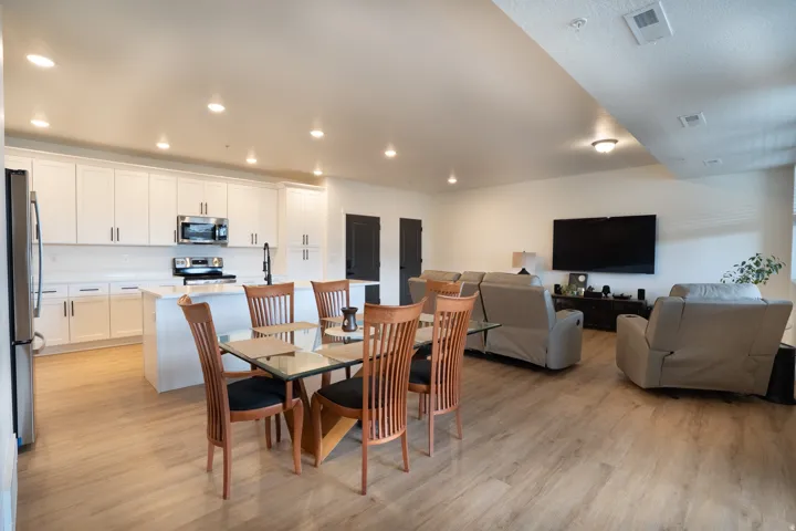 Open-concept living area featuring wood-finish flooring, recessed lighting, a white kitchen island, and stainless steel kitchen appliances