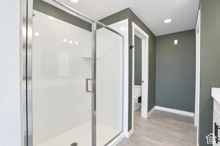 Primary suite shower with glass-enclosed shower with a white surround and stainless steel hardware