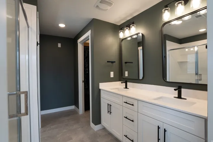 Primary bathroom with dual vanity with white cabinetry, matte black hardware, and integrated sinks