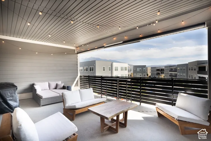 Covered balcony with slatted ceiling, string lighting, and a slatted metal railing provides privacy and mountain views.