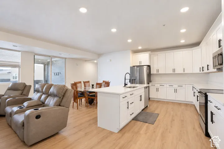 Kitchen with massive white shaker cabinets, living room, and dining room. View from the front door