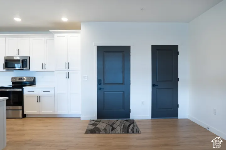 Front door and closet with kitchen cabinets next to it.