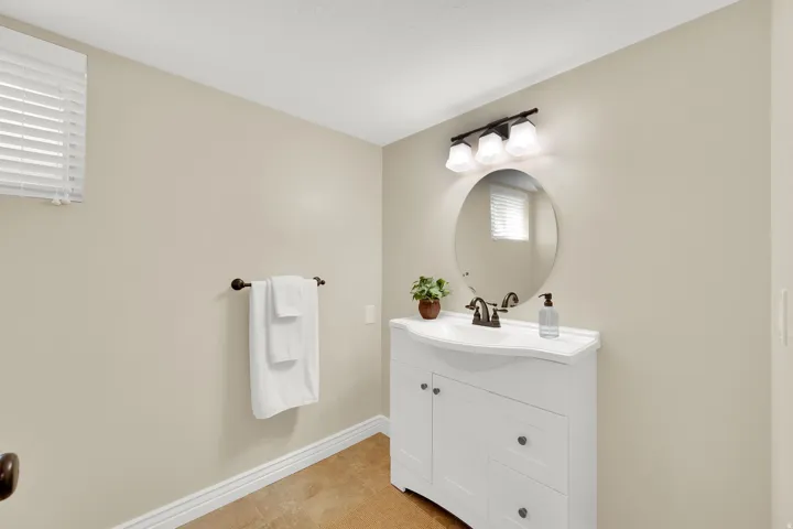 White vanity with an integrated sink, bronze-finish faucet, and coordinating oval mirror
