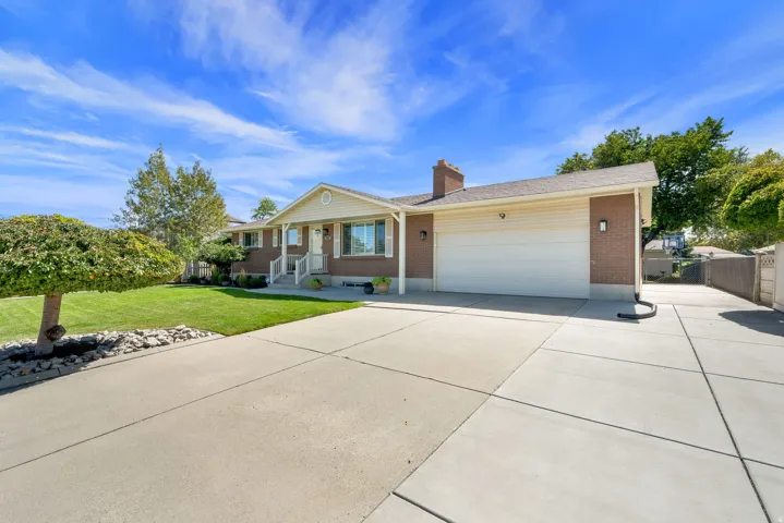 Brick exterior with white siding accents, a two-car garage, concrete driveway, and established front landscaping
