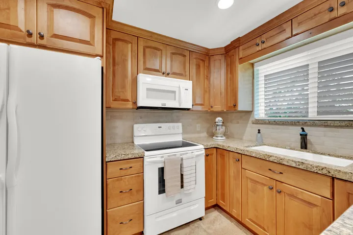Wood-finish cabinetry paired with light-toned countertops and a matching backsplash