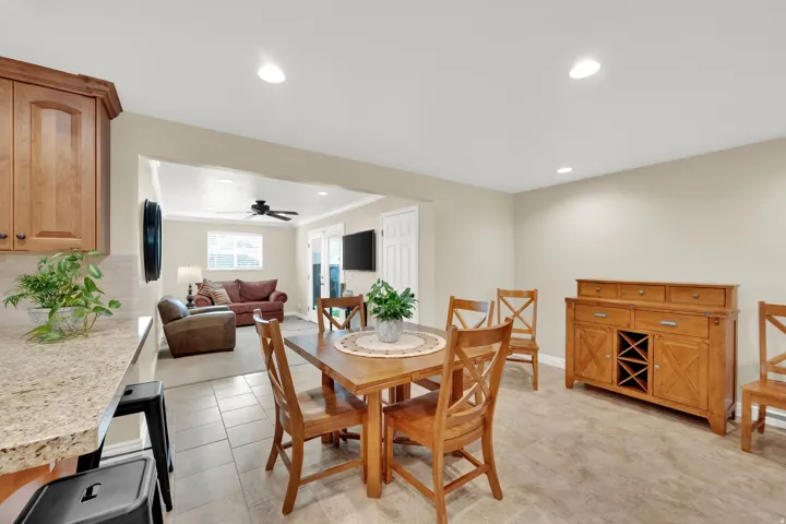 Open-concept living space featuring recessed lighting, a kitchen pass-through with granite-look countertop, and tile flooring