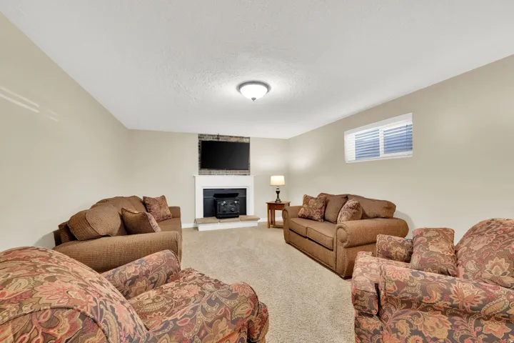 Carpeted flooring, recessed window, white trim, wall-mounted light fixture, and a fireplace with a white mantel and hearth