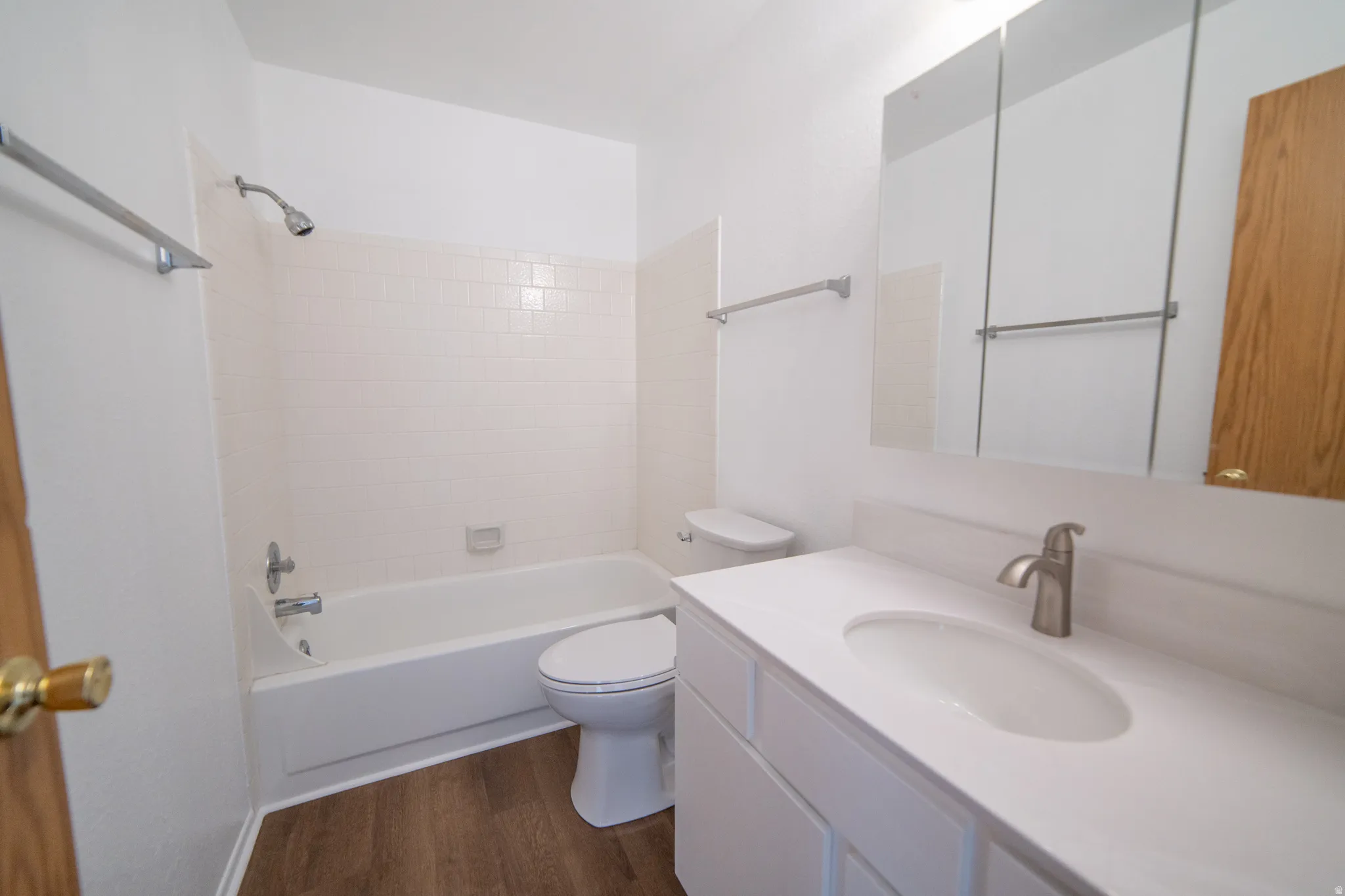 Wood-finish flooring with a white vanity featuring a single basin and chrome faucet