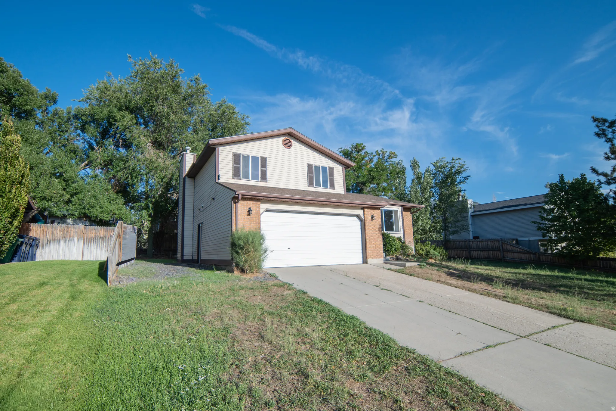 Two-story residence featuring a two-car garage, brick facade accents, and a concrete driveway
