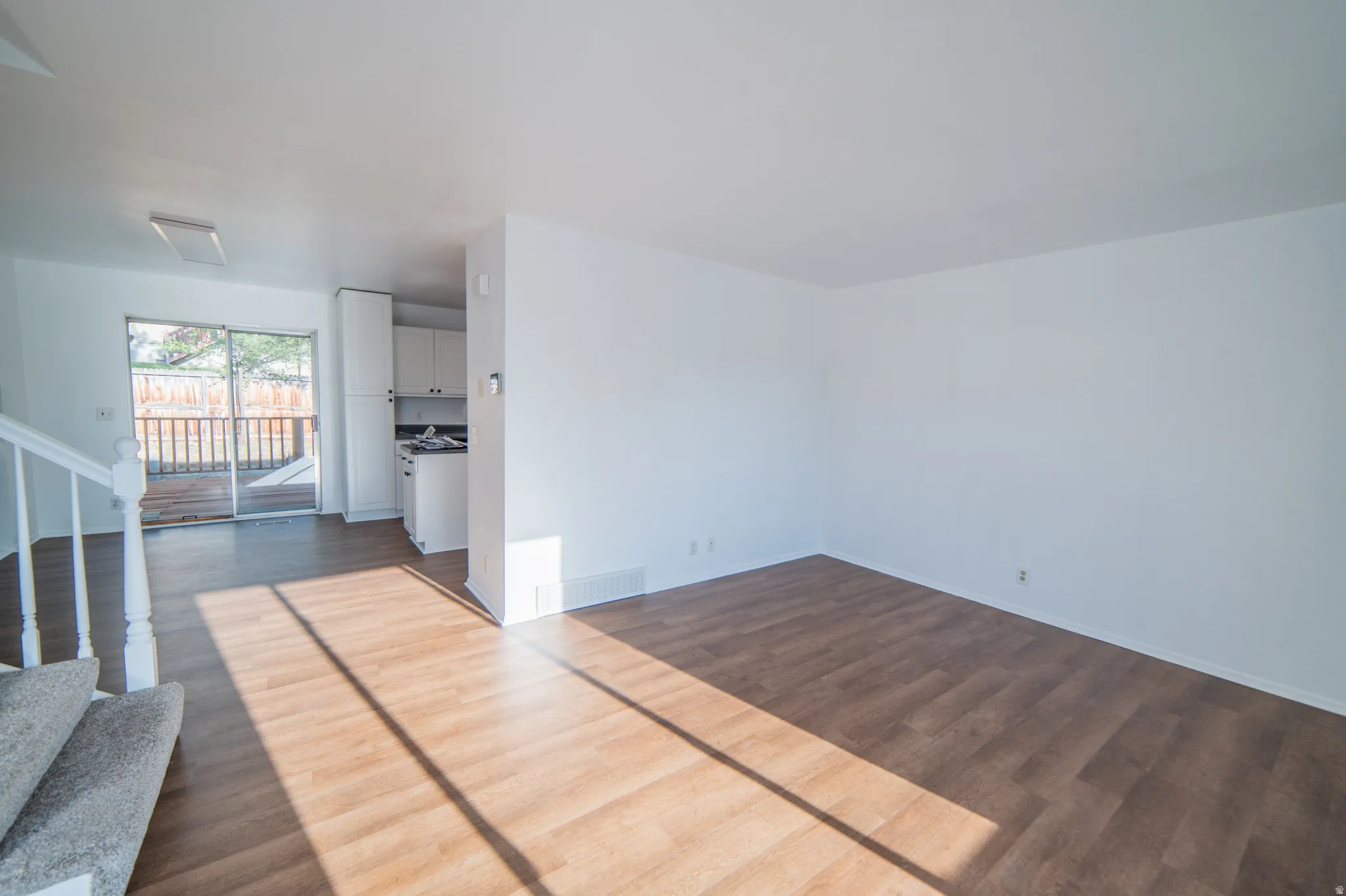 Open living space with wood-finish flooring, white walls, and bright natural light