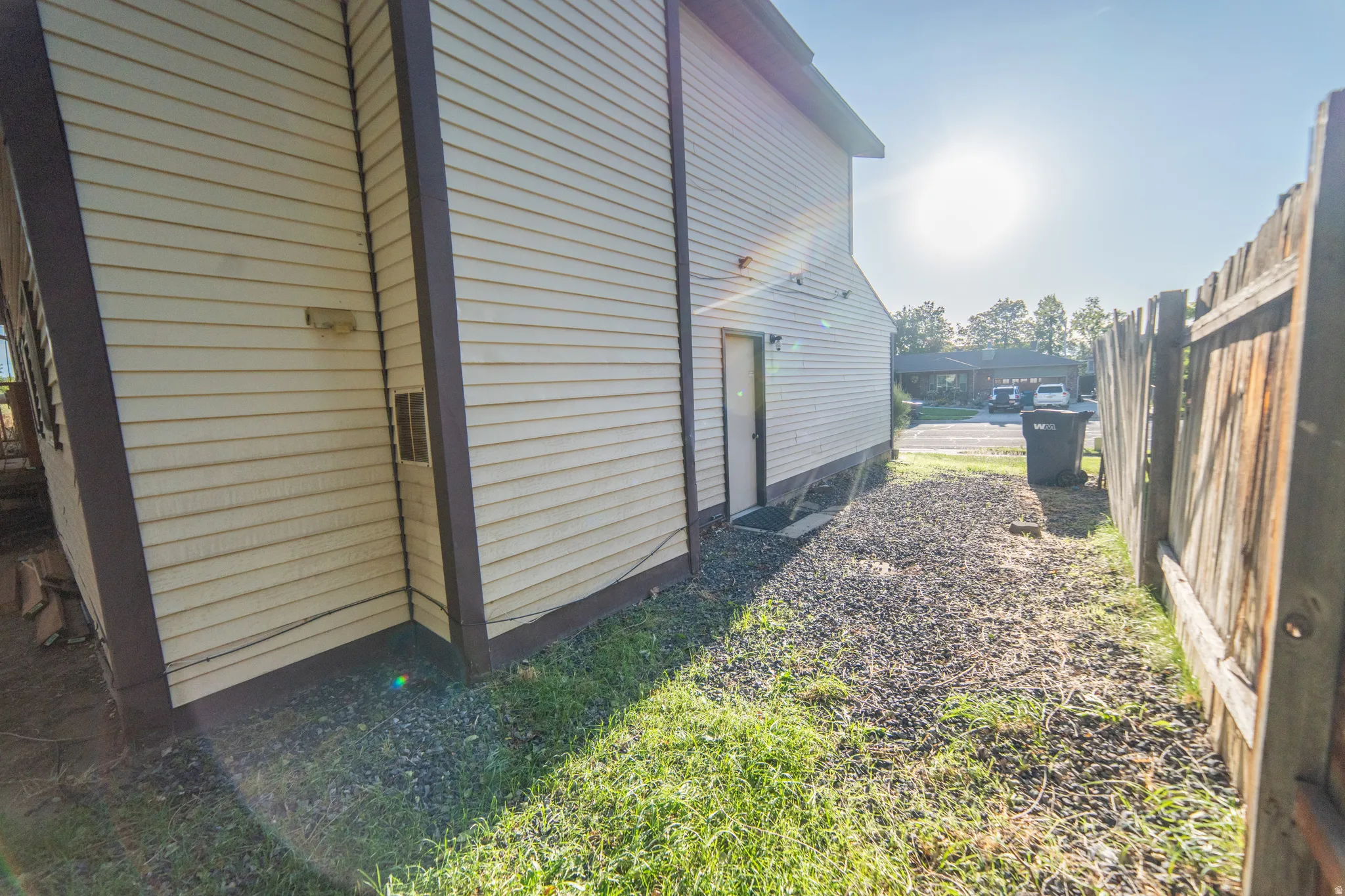 Siding exterior with trim details, gravel pathway, and privacy fencing