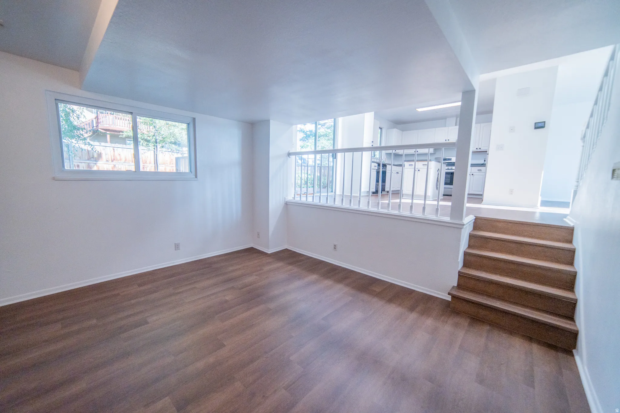 Wood-finish flooring, white walls, white window trim, and white painted railings