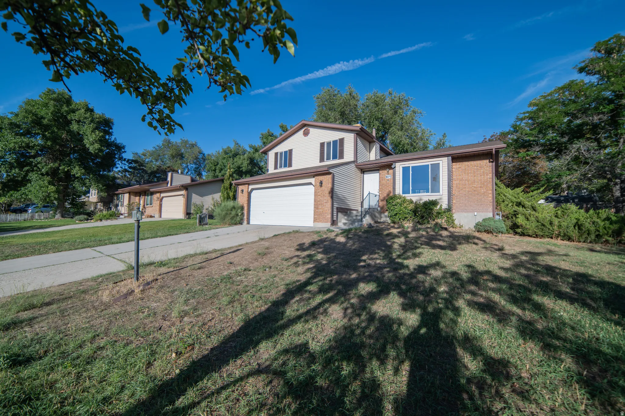 Split-level exterior featuring brick and siding, a two-car garage, and a concrete driveway