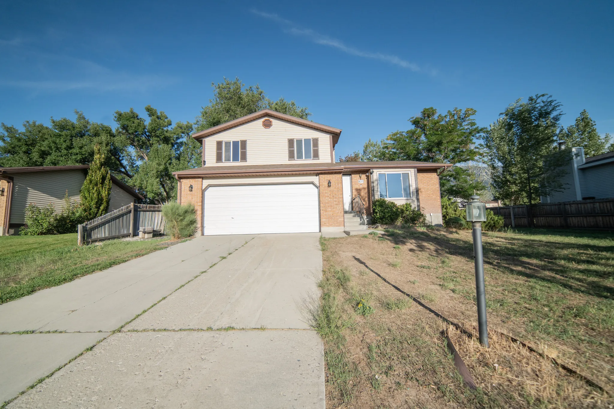 Two-story residence featuring a two-car garage, brick and siding exterior, and a concrete driveway