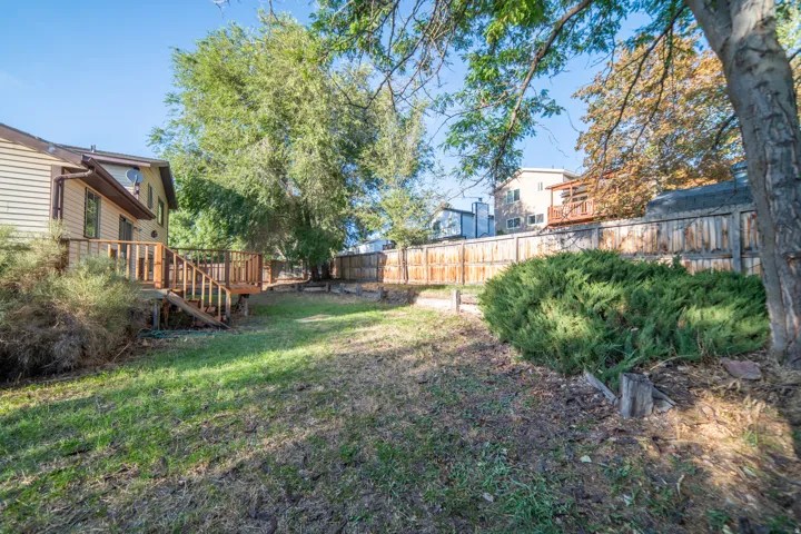 Expansive yard with wood fencing, mature trees, and a multi-level wood deck