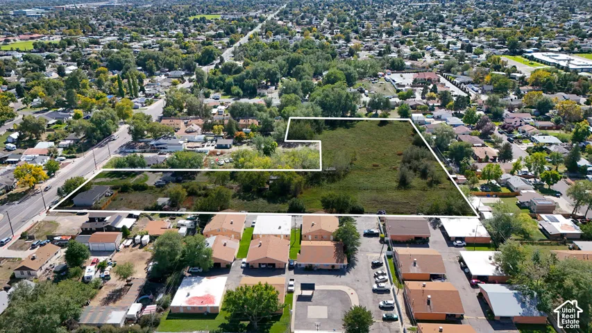 Expansive land parcel featuring existing structures, surrounding residential areas, and mature trees