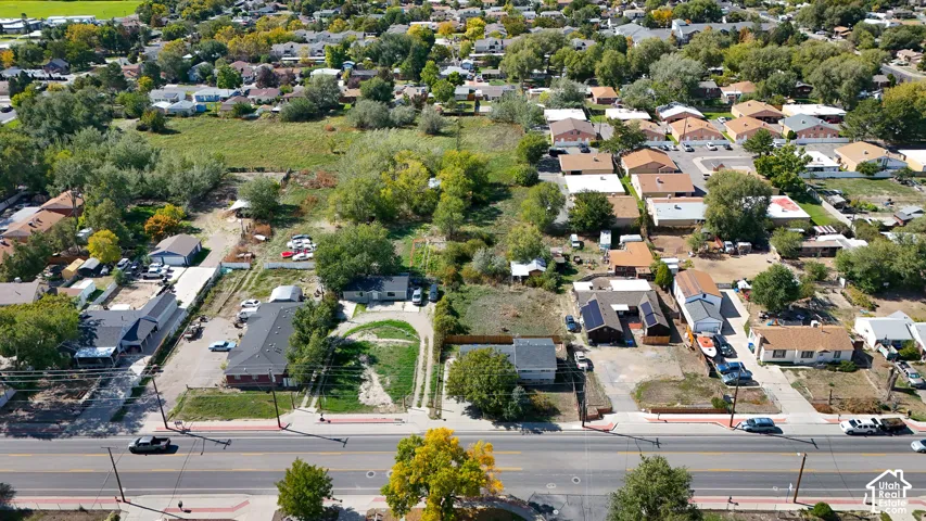 Expansive land parcel with surrounding residential properties, mature trees, and a developed roadway