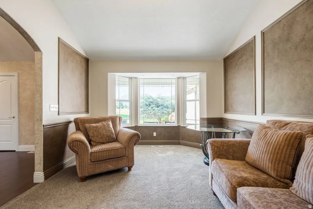 Bright corner bedroom suite with bay window seating area, dual built-in window benches with cushioned seating, neutral carpet flooring, and textured accent walls