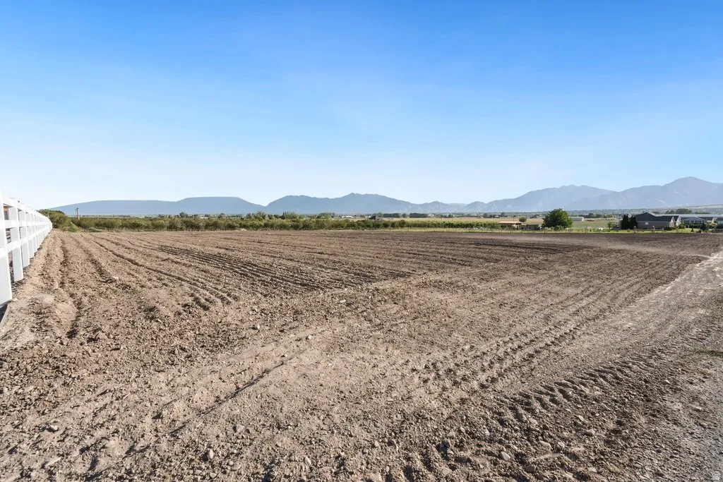 Expansive cleared lot with a white perimeter fence and distant mountain scenery