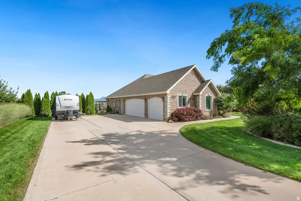 Brick exterior with a gabled roofline, three-car garage, and mature landscaping