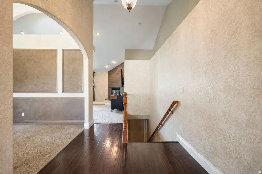 Archway entry, wood-finish flooring, textured wall finishes, recessed lighting, and a wood-paneled fireplace surround