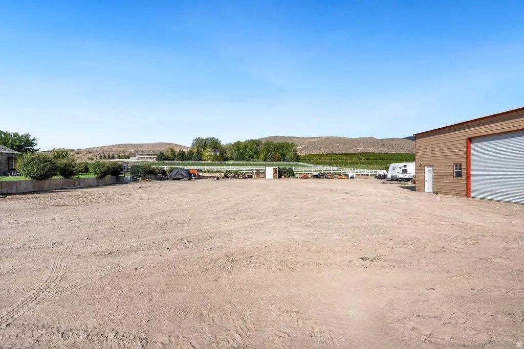 Expansive cleared lot with a large utility building featuring a roll-up door and a standard entry door