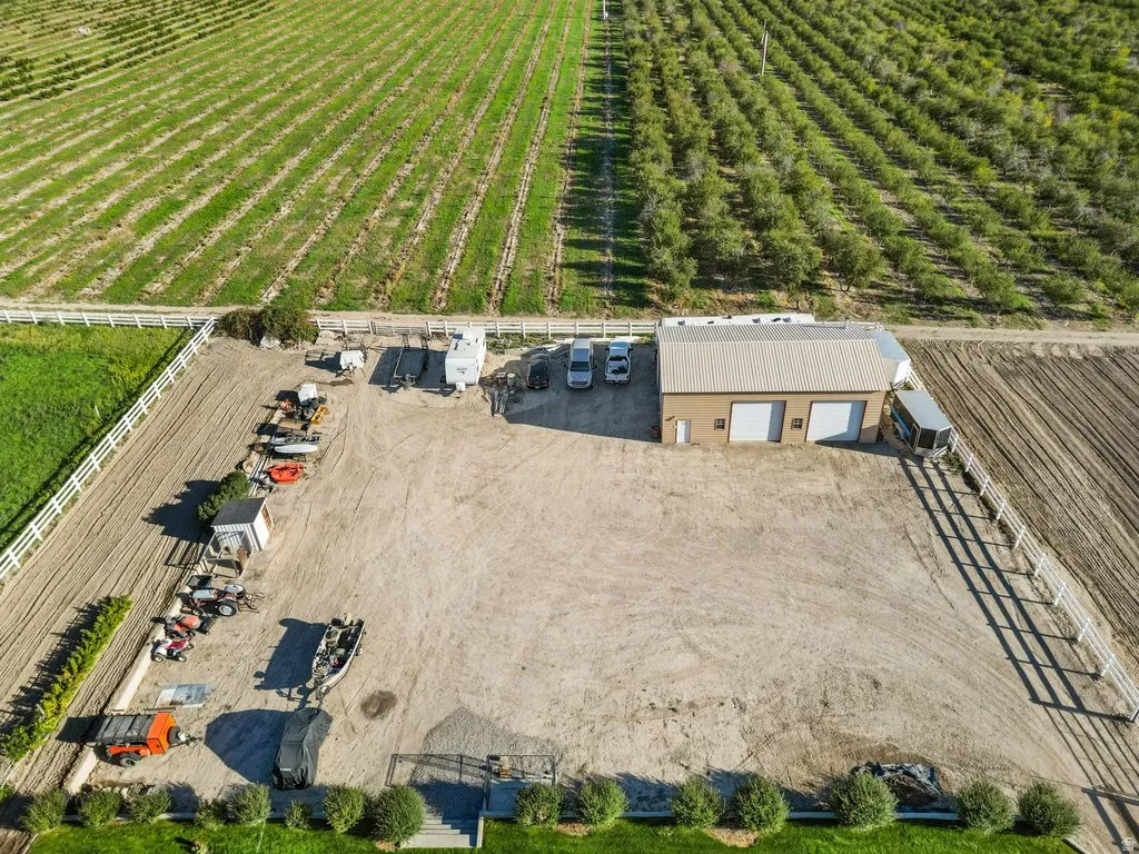 Expansive property featuring a large open lot, a  three-bay garage structure, and perimeter fencing