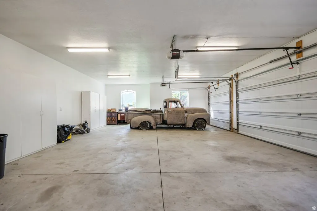 Spacious garage with concrete flooring, overhead lighting, and multiple storage cabinets  Antique truck is not for sale.