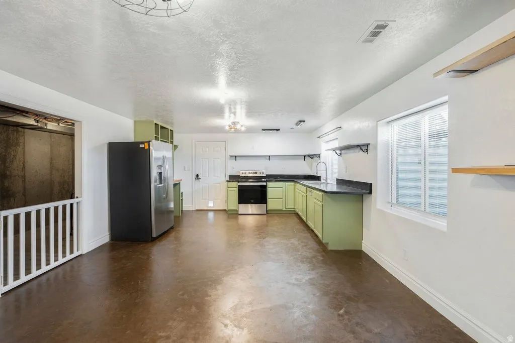 L-shaped kitchen with green cabinetry, dark countertops, stainless steel appliances.