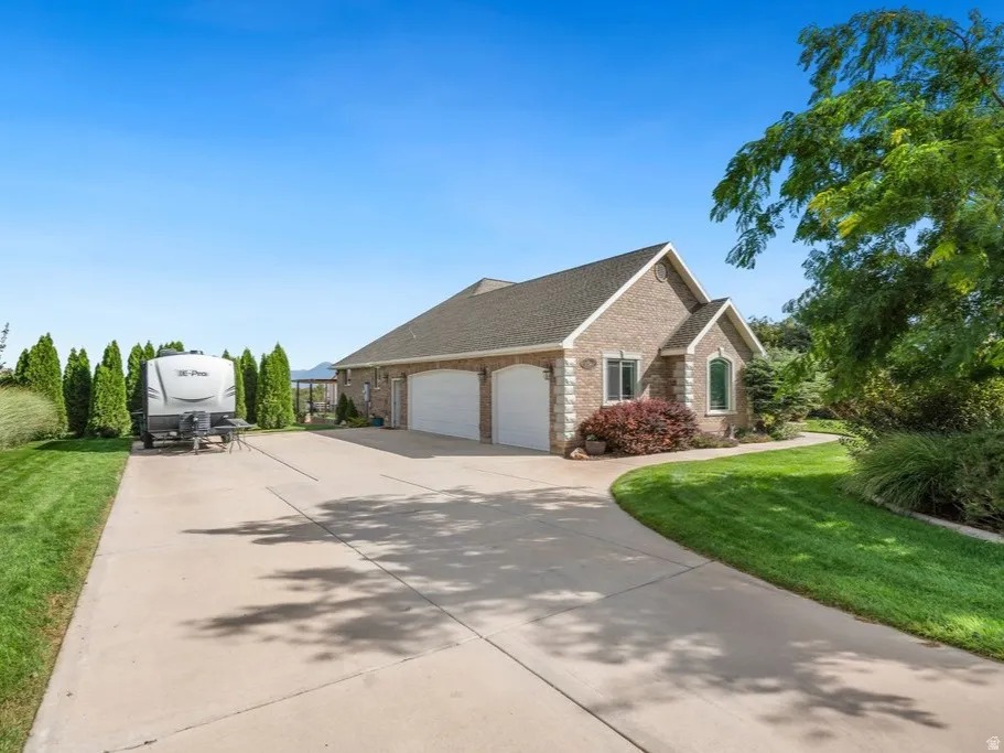 Brick exterior with a gabled roofline, three -car garage, and mature landscaping