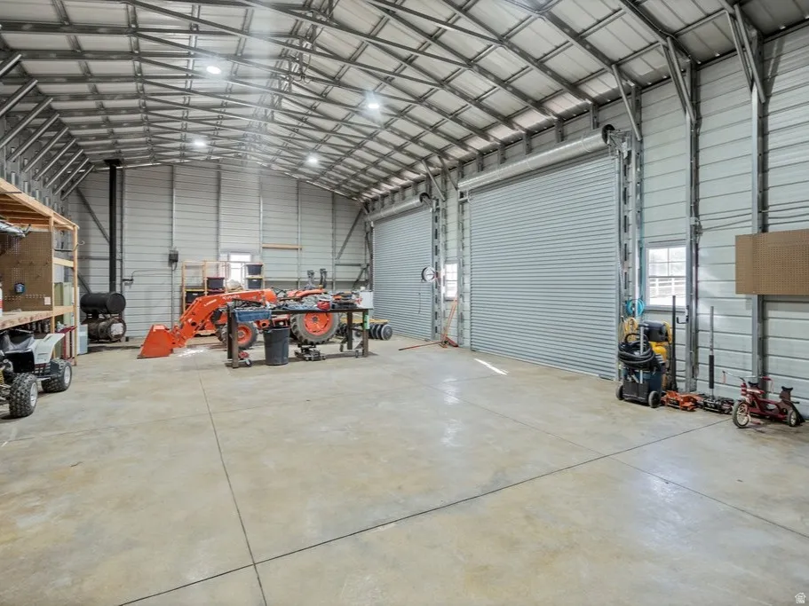 Spacious interior with radiant heating in the concrete floor, metal truss ceiling, recessed lighting, and three large roll-up doors
