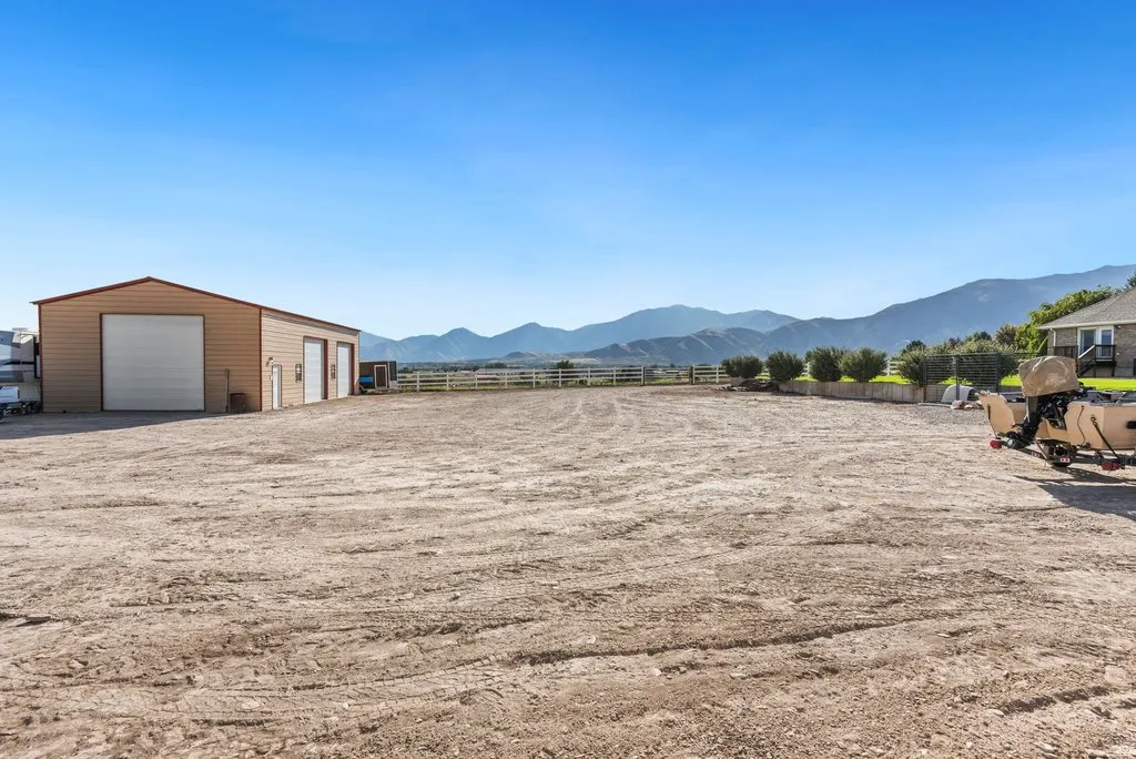 Large open lot with a tan and red-trimmed outbuilding featuring three garage doors